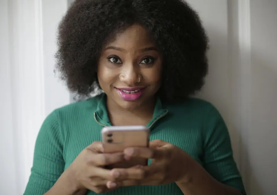 Mulher sorrindo enquanto usa o celular